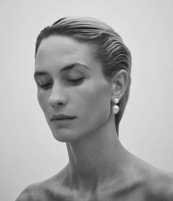 Retrato sereno de uma mulher de olhos fechados, em tons neutros e quentes